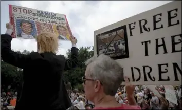  ?? NICK WAGNER/AUSTIN AMERICAN-STATESMAN VIA AP ?? Heidi Turpin (left) dressed as President Donald Trump, holds up a sign next to her husband, Jim, during a protest against detaining migrant children, Thursday, in Austin, Texas.