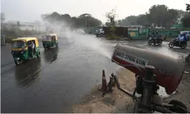  ?? Money Sharma/AFP/Getty Images ?? Commuters pass an anti-smog gun spraying water to curb air pollution in Delhi. Photograph: