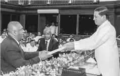  ??  ?? Samaraweer­a (left), who has been foreign minister since January 2015 takes an oath as he is sworn in as Minister of Finance in front of Sirisena. — Reuters photo