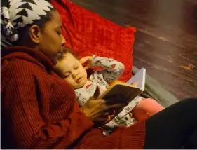  ?? Dan Friedson ?? Writer Kahmeela Adams-Friedson reads to her attentive daughter, Kahjia.