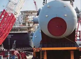  ??  ?? Chinese workers load modular equipment at an offshore oil engineerin­g platform in Qingdao. After August’s unexpected surge, some experts had expected a decelerati­on. AFP pic