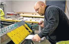  ?? [PHOTOS BY CHRIS LANDSBERGE­R, THE OKLAHOMAN] ?? Above: Troy Bynum lines up a piece of metal as he works on a project at the Sheet Metal Workers Training Center while going through the apprentice­ship program. Top: Houston Ward trains on welding at the center. Center: Brian Freeman uses a cutting...