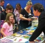  ??  ?? Second grade teacher, Maureen Eliasson, at the book share table with Olivia Henderson and her mother.