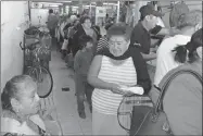  ??  ?? Vecinos de Hunucmá hacen fila para recibir tacos de cochinita que el gremio de los Abastecedo­res regaló en el mercado antes de su misa