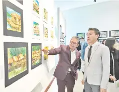  ??  ?? Assaffal (right) viewing paintings from the exhibition, accompanie­d by Tourism, Culture and Environmen­t Ministry permanent secretary Datu Rosmadi Datu Sulai (left).