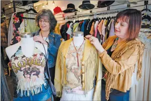  ?? CP PHOTO ?? Theresa Morgan, left, and Bonnie Barber, owners of A Vintage Affair, with some of their western wear for the thrifty Stampede goer in Calgary, Alta., Tuesday, July 5, 2016. For Calgarians hit by the economic slump, it may not be the best time to spend hundreds of dollars on a brand new pair of leather cowboy boots.