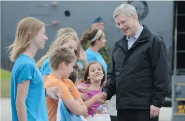  ?? SEAN KILPATRICK/THE CANADIAN PRESS ?? Prime Minister Stephen Harper is welcomed by children at a summer camp on Monday as he arrives in Hay River, Northwest Territorie­s, where he unveiled $5.8 million in federal funding for a mining training program.