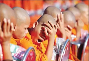 ?? HONG MENEA ?? A young monk yawns as temperatur­es rise during a religious ceremony on Saturday at Siem Reap’s Angkor Wat temple.