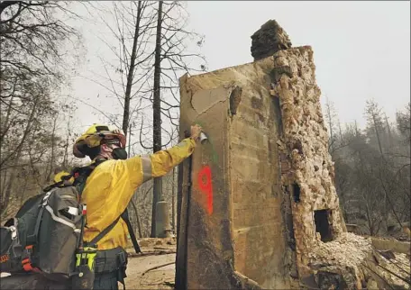  ?? Carolyn Cole Los Angeles Times ?? BEN ARNOLD of the Los Angeles Fire Department marks a burned home in the wake of the North Complex fire in rural Butte County on Thursday. Crews are still working to contain the blaze, now the fifth-largest and among the deadliest in California history.