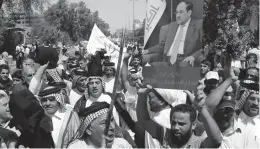  ??  ?? Iraqis chant pro- government slogans and wave national flags to show support for PM Nouri al- Maliki during a demonstrat­ion in Baghdad on Saturday. —