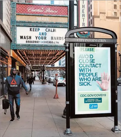  ?? JOHN J. KIM/CHICAGO TRIBUNE ?? Signs for sanitation and social distancing are displayed on a theater marquee and a public service announceme­nt March 17 in Chicago.