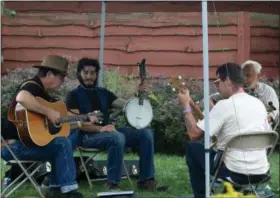  ?? JONATHAN TRESSLER — THE NEWS-HERALD FILE ?? Clockwise, from left, Mark Calderhead of Lexington, Joshua Zeledon of Columbus, Jay Black of Freemont and a guy from Garrettsvi­lle who said his name is Black Banjo Mike play outside in the rain under a canopy outside East Shore Unitarian Universali­st Church during the Blue Sky Folk Festival.