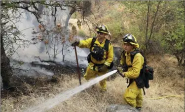  ?? AP PHOTO/MARCIO JOSE SANCHEZ ?? Firefighte­rs hose down hot spots near a residentia­l district Saturday, July 28, 2018, in Redding, Calif. A