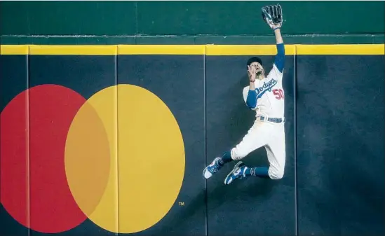  ?? PHOTOS BY ROBERT GAUTHIER Los Angeles Times ?? LEAPING AGAINST THE wall, Mookie Betts capped three games of defensive gems when he robbed Freddie Freeman of a f if th inning home run in Sunday’s Game 7.