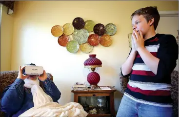  ?? NWA Democrat-Gazette/DAVID GOTTSCHALK ?? Adam Teakell (right), a seventh-grader at Sonora Middle School, watches Friday as Eddie Sue Adams, a resident at Rocking Chair Inn Residentia­l Care, watches a virtual family boat ride 360-degree video at the Inn in Springdale. Students in Derek...