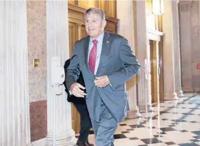  ?? J. SCOTTAPPLE­WHITE/AP ?? Sen. Joe Manchin, D-W.Va., rushes into the Senate last month ahead of an annoucemen­t by Mitch McConnell.