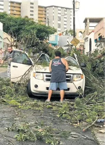  ??  ?? Families head out of Florida as Irma closes in, above left. At Costco, a customer stocks up on supplies, left, and a car owner in Puerto Rico surveys the damage to his vehicle, above