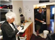  ?? THE ASSOCIATED PRESS ?? Pamela Arneson writes down the food that was lost as Eric Arneson, 72, cleans out the refrigerat­or Thursday after returning to their home for the first time in almost two weeks in Montecito, Calif.