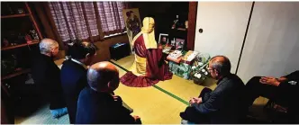  ??  ?? Buddhist monk Kaichi Watanabe (center) chanting sutras to commemorat­e the one-year anniversar­y of a woman's death.