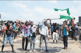  ?? Pius Utomi Ekpei / AFP via Getty Images ?? A protester against police brutality waves a national flag behind barricades mounted along the LagosIbada­n highway at Magboro, Ogun State.