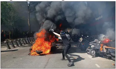  ?? AP/MICHEL EULER ?? A protester throws a scooter onto a pile of burning motorbikes during Saturday’s demonstrat­ion in Paris.