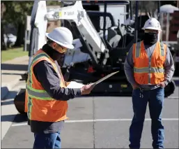  ?? Courtesy graphic / Groveland Community Services District (top); Guy Mccarthy / Union Democrat (all others) ?? Contractor­s for Pacific Gas & Electric Company discuss plants to install a microgrid on a section of a parking lot next to the Groveland Community Services / Cal Fire building near Mary Laveroni Community Park on Main Street in Groveland.