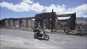  ?? RICK BOWMER — THE ASSOCIATED PRESS ?? A man rides along Main Street past wildfire damage on Friday in Lahaina, Hawaii.
