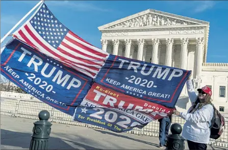  ?? J. SCOTT APPLEWHITE / AP ?? Kathy Kratt of Orlando, Fla., displays her Trump flags as she and other protesters demonstrat­e their support for President Donald Trump at the Supreme Court in Washington, Friday, where the high court rejected a lawsuit backed by President Donald Trump to overturn Joe Biden’s election victory.