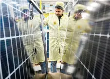 ?? ?? An employee inspecting solar panels at an Adani Group factory.