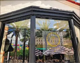  ?? BALMASEDA / THE PALM BEACH POST PHOTOS BY LIZ ?? The umbrellas beam their images onto storefront­s, sunglasses and cellphone screens across the promenade. Here, they peek into the popular Threefold Cafe.