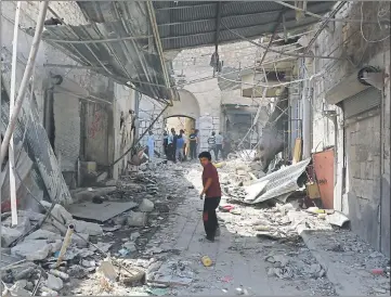  ??  ?? DEVASTATIO­N: A boy walks past the damage after a Syrian army fighter jet crashed into a busy marketplac­e in a rebel-held town.