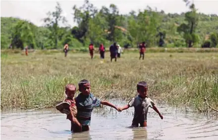  ?? REUTER PIC ?? Rohingya children wading through water as they make their way to Cox’s Bazar in Bangladesh yesterday.