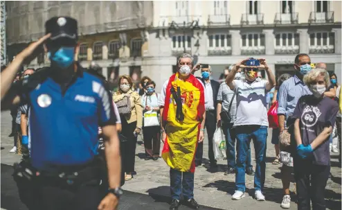  ?? Manu Fernan
dez / the asociat ed press ?? People hold a minute of silence for the victims of COVID-19 in downtown Madrid on May 27 as flags flew at half-mast
on more than 14,000 public buildings in Spain while the nation held its first of 10 days of mourning.