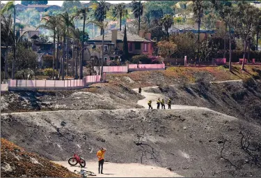  ?? ?? Firefighte­rs and residents stand Thursday on a fire road where the Coastal Fire jumped and burned several homes in Laguna Niguel.