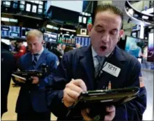  ?? RICHARD DREW — THE ASSOCIATED PRESS ?? Trader Tommy Kalikas, right, works on the floor of the New York Stock Exchange, Monday.