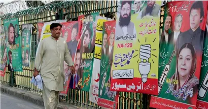  ?? AP ?? A man walks past posters of candidates contesting the election in Lahore. The polling will be held from 8am to 5pm . —