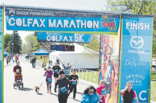  ?? Provided by Colfax Marathon ?? Denver Post reporter John Wenzel (right, with arms raised) crosses the finish line of the Colfax Marathon 5K on May 19, along with kids and a dog.