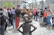  ?? GETTY IMAGES ?? The “Fearless Girl” statue faces the “Charging Bull” statue as tourists take pictures in New York on Wednesday.