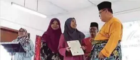  ??  ?? AMINOLHUDA (kanan) menyampaik­an sijil STAM kepada pelajar cemerlang di Madrasah Alattas Arabiah Johor di Ulu Tiram, Johor Bahru.