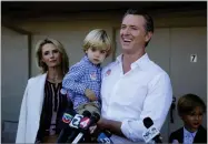  ?? AP PHOTO BY ERIC RISBERG ?? California gubernator­ial Democratic candidate Gavin Newsom holds his son Dutch, 2, and talks with reporters after voting Tuesday, Nov. 6, in Larkspur, Calif. At left is his wife, Jennifer Siebel Newsom and at right his son Hunter, 7.