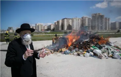  ?? ?? BURNING CHAMETZ collected by the Jerusalem Municipali­ty, with the city’s Chief Ashkenazi Rabbi Aryeh Stern in attendance, April 2020. (Yonatan Sindel/Flash90)