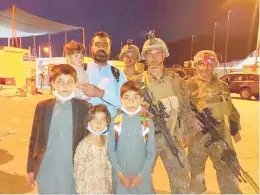  ?? COURTESY PHOTO ?? Atif Ahmadzai stands with four of his five children and U.S. Marines after he gained entry to the internatio­nal airport in Afghanista­n that paved the way for their trip to the United States after the fall of Kabul. They are seeking to reach New Haven. His wife was with them, but is not pictured here.