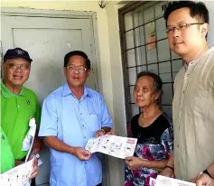  ??  ?? Tan (second left) distribute­s a dengue awareness pamphlet to a resident. Also seen are Thian (left) and MBKS councillor Bong Lian Huan.