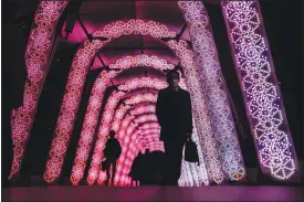  ?? (AP/Kiichiro Sato) ?? People walk through a tunnel of holiday light displays Dec. 9 in Tokyo.