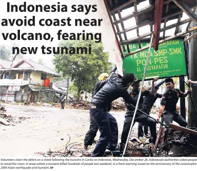  ?? AP ?? Volunteers clean the debris on a street following the tsunami in Carita on Indonesia, Wednesday, Dec.ember 26. Indonesian authoritie­s asked people to avoid the coast, in areas where a tsunami killed hundreds of people last weekend, in a fresh warning issued on the anniversar­y of the catastroph­ic 2004 Asian earthquake and tsunami.