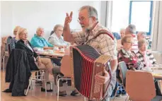  ?? SZ-FOTO: DK ?? Helmut Schröm sorgte mit seinem Akkordeon einmal mehr für gute Stimmung. Hilde Mattheis (hinten links) kam ungezwunge­n mit den Besuchern bei Kaffee und Kuchen ins Gespräch.