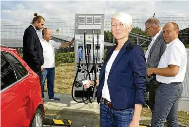  ??  ?? Alexandra Kästner lädt ihren Audi Hybrid, während sich HEM-Bezirkslei­ter Ralf Karbaum und der Tankstelle­npächter Norbert Kettner sowie Projektent­wickler Andreas Schönleber und Bürgermeis­ter Marko Bias (hinten von links) unterhalte­n. Die HEM Muttergese­llschaft Deutsche Tamoil GmbH hat am Montagnach­mittag an der HEM-Tankstelle Schleiz eine Schnelllad­esäule für Elektrofah­rzeuge in Betrieb genommen. Foto: Peter Cissek