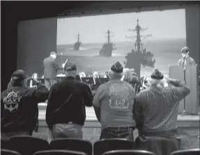  ?? Susan Holland/Westside Eagle Observer ?? United States Navy veterans stand as the Gravette High School band plays “Anchors Aweigh,” the marching song of the U.S. Navy, during the school’s Veterans Day assembly Friday, Nov. 9. Pictured are James Evans (left), James Brooks, Al Blair and Bill Matney, members of the John E. Tracy American Legion Post 25.