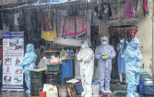  ??  ?? Health workers wearing personal protective equipment (PPE) take shelter while conducting a COVID-19 screening in heavy rain, Mumbai, India, Aug. 12, 2020.