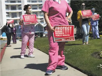  ?? Lea Suzuki / The Chronicle ?? Environmen­tal worker Adela Melara (left of center) and registered nurse Lizzy Ma (right of center) rally for additional protective equipment at Seton Medical Center in Daly City.